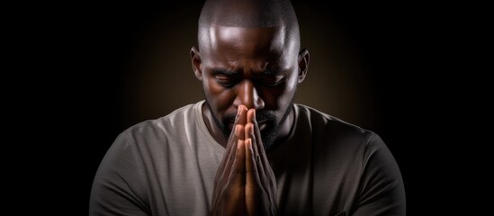 Reflective man with hands clasped kneeling in prayer deep in meditation - obrazy, fototapety, plakaty