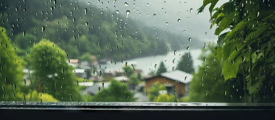 Fotobehang Tranquil Rainy Day Scene with Water Droplets on a Window and Lush Trees Outside © vxnaghiyev