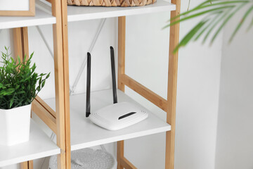 Modern wi-fi router on shelf near light wall, closeup - obrazy, fototapety, plakaty