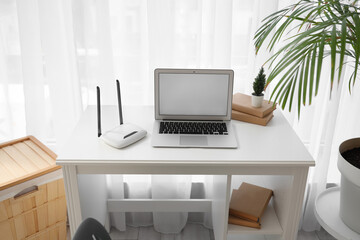 Workplace with laptop and wi-fi router in room