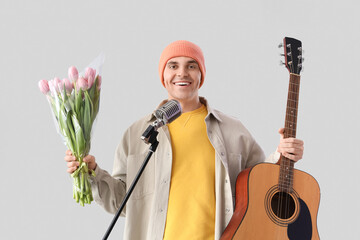 Male artist with tulips and guitar singing on light background. International Women's Day celebration - Powered by Adobe