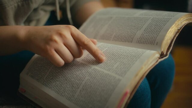 Woman slowly reading bible in home environment