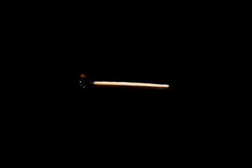Lit falling match on a black background.