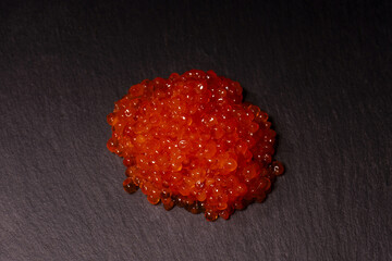 Red trout caviar on a black background.