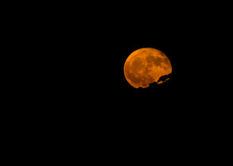 Full Orange Harvest Moon rising over the darkened Spanish countryside.