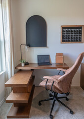 Vertical shot of home office with wood computer desk with leather chair in front of window