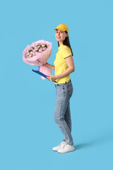 Young delivery woman with bouquet of beautiful roses and clipboard on blue background