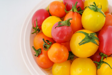 Fresh small persimmons of various colors on white background