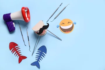 Fotobehang Megaphone with model of jaw, dentist tools and paper fishes on blue background. April Fools Day © Pixel-Shot