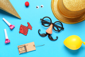 Funny glasses with paper fish, mousetrap and party decor on blue background. April Fools Day