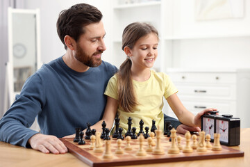 Father teaching his daughter to play chess at home