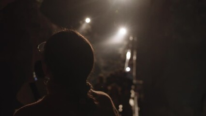 Girl with glasses as part of a tour group inspects a cave