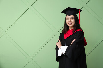Happy female graduating student on green wooden background