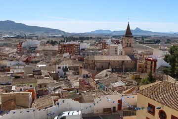 Villena, Alicante, Spain, March 5, 2024: Houses around the Church of Santa Maria with the mountains...