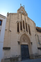 Fototapeta na wymiar Villena, Alicante, Spain, March 5, 2024: Door, windows and bell tower of a church in the Plaza de las Malvas in Villena, Alicante, Spain
