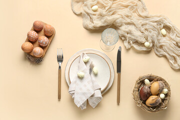 Beautiful table setting and nest with Easter eggs on beige background