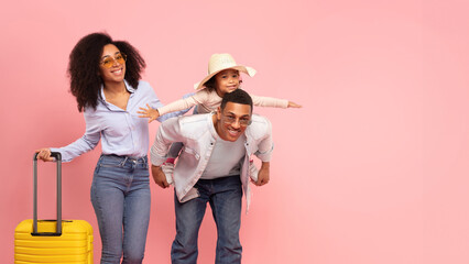 Happy black family ready for travel, father giving piggyback ride to daughter, parents and girl...