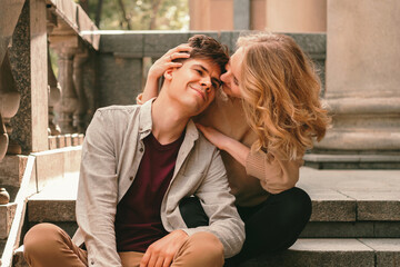 Young couple are spending time together while sitting outdoors on some stairs.