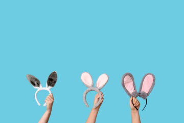 Female hands holding Easter bunny ears headbands on blue background