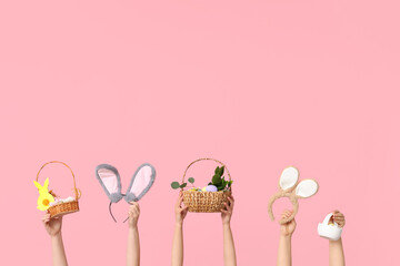 Female hands holding Easter bunny ears headbands with baskets on pink background