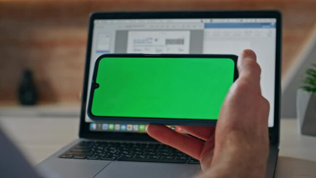Man touching chroma key mobile phone in horizontal position at workplace closeup