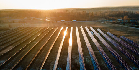 Aerial view of industrial sized solar panel farm during sunset,  illustrating the blend of...