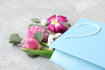 Paper shopping bag with flowers and eucalyptus on grey grunge background