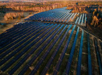 Aerial view of industrial sized solar panel farm during sunset,  illustrating the blend of...