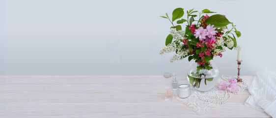 panorama vibrant bouquet of blossoming cherry in glass vase on table, bird cherry, candles, lady's...