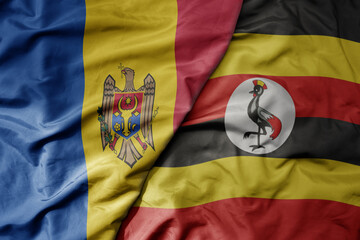 big waving national colorful flag of uganda and national flag of moldova .