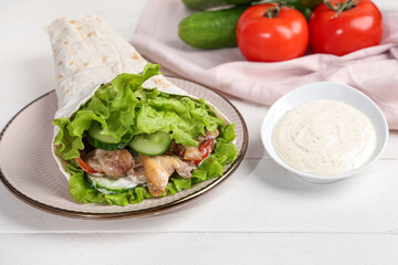 Plate with tasty doner kebab and sauce on white wooden background