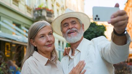 Smiling happy Caucasian old senior retired family couple travelers tourists taking selfie photo on...