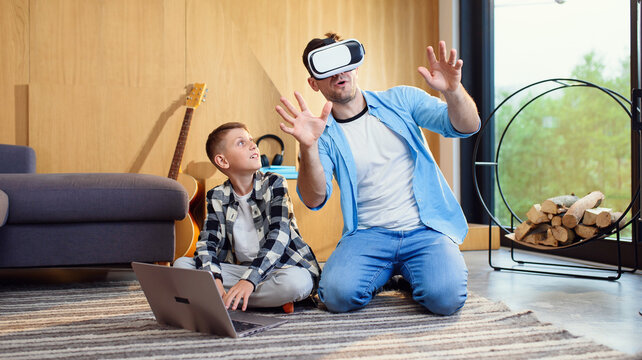 Happy young father and son testing vr goggles playing augmented video reality games.