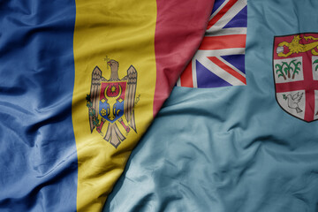 big waving national colorful flag of Fiji and national flag of moldova .