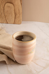 Coffee mug in a marbled stone background with beige napkin in front view