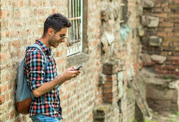 Handsome man sending text message. Young man standing outdoors and texting .