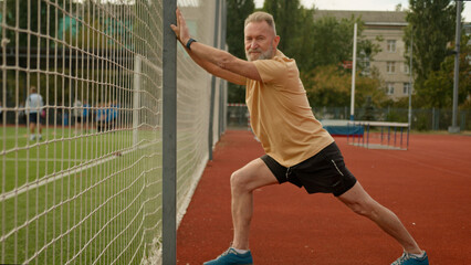 Obraz premium Elderly Caucasian man pensioner athlete outside city stadium physical activity sport flexibility exercise sportsman fitness strong cardio strength recreation energy gymnastic healthy lifestyle aerobic