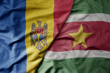 big waving national colorful flag of suriname and national flag of moldova .