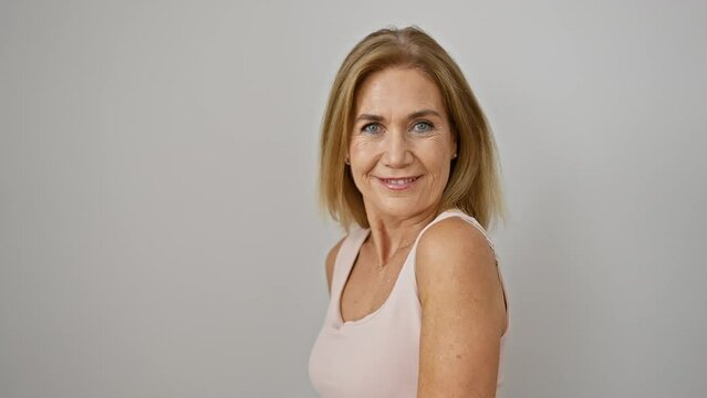 Portrait of a smiling mature woman with blonde hair against a white background, embodying beauty and positivity.