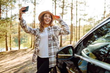 Selfie in nature. Woman tourist standing near car and enjoy nature. Active lifestyle, travel.
