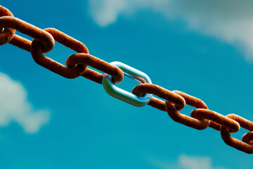 Rusty and Shiny Chain Links Intertwined Against a Vibrant Blue Sky