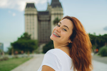young red haired latin woman in the city smiling and with complicity looks at the camera. copy space