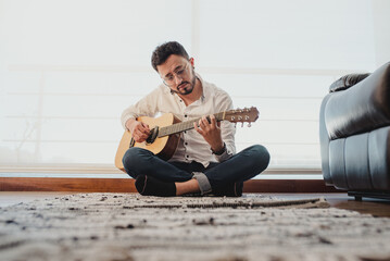 "Intimate creative moment: musician writing songs sitting on wooden floor"

