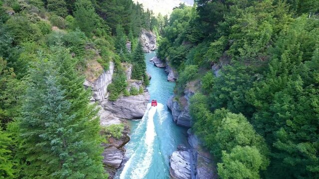 Speedboat jet boat in river in canyon. New Zealand extreme sport for thrill seekers, adventure travel, backpacking. 