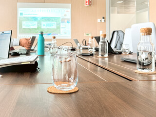 Modern meeting room with a projection on the wall and a glass of water in the foreground - 753302120