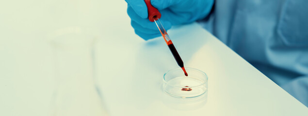 Scientific laboratory researcher drop blood sample on microscopic slide for medical examination or...