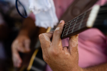 Detail of hands playing a guitar with nylon strings.
