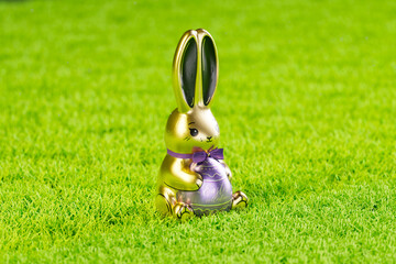 Gleaming Gold Easter Bunny with Purple Ribbon on Lush Grass