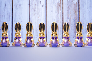 Gleaming Golden Easter Bunny Figurines Lined on Blue Wooden Surface