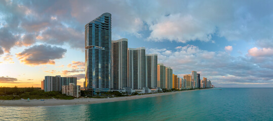 Expensive highrise hotels and condos over sandy beachfront on Atlantic ocean shore in Sunny Isles Beach city at sunset. American tourism infrastructure in southern Florida